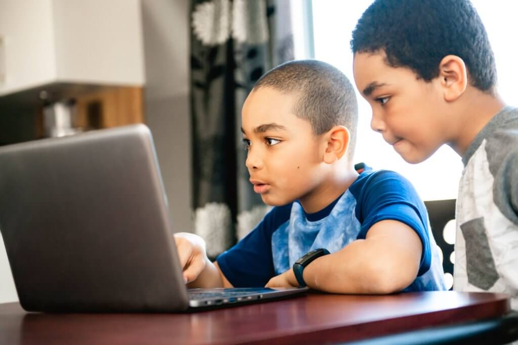 Zwei Kinder die auf einem Laptop arbeiten
